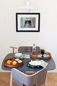 Black-and-white striped chairs at small table below picture on wall