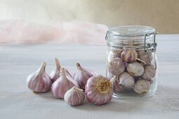 Fresh garlic bulbs in and next to swing-top jar