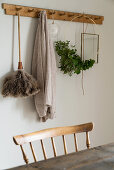 Feather duster, wreath of leaves and cardigan hanging from wooden coat rack