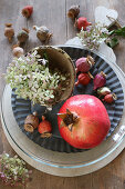 Autumnal table decoration of pomegranate, poppy seed heads and hydrangeas