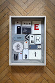 Collection of tags with graphic motifs in in fabric-lined display case