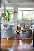Hund im exotischen Wohnzimmer mit hellblauem Sofa und Fensterfront