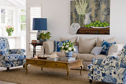 Polstermöbel mit weiß-blauem und mit sandfarbenem Bezug um Couchtisch im Wohnzimmer