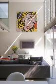 Pop Art picture on wall in seating area with sofa and TV in interior with high ceiling and gallery