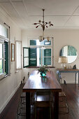Dark wooden dining table, wooden floor and blue shutters in vintage-style interior