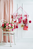 Blumenbouquet auf Stuhl dahinter DIY-Adventskalender in Weiß, Rot und Rosa