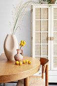 Grasses and fruits in vases on round table in dining room