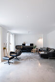 Leather armchair, piano and sofa in living room with screed floor
