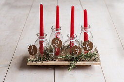 Selbstgemachter Adventskranz aus roten Kerzen in Glasflaschen