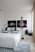 Sculpture and photos of hands above bed in bedroom