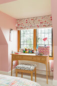 Schreibtisch vor Sprossenfenster im Zimmer mit rosa Wänden