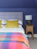 Double bed and bedside cabinet in room with blue walls