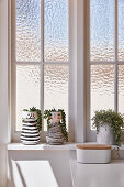 Planters with faces on sill of lattice window with textured glass