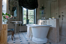Free-standing bathtub next to half-height partition in French-style bathroom