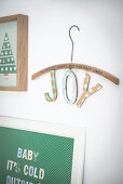 Christmas decorations: Two collages and letters spelling 'Joy' hung from wooden coat hanger