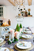 Table set for Christmas with small potted conifers and pillar candles