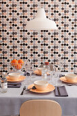 Set dining table in front of wall with grey, black and pink wallpaper with graphic pattern