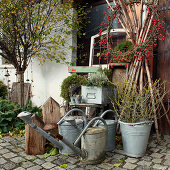 Autumn arrangement with a wreath of rose hips, zinc watering cans, and zinc buckets with branches
