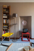 Yellow stool, book shelved and standard lamp next to niche