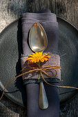 Silver spoon and pot marigold tied to napkin with jute ribbon and twine