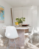 Shell chairs at table in front of fitted cupboards in white dining room