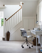 Desk in front of staircase with fitted under-stair cupboards in foyer