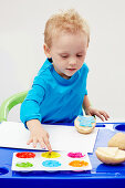 Little by making potato prints with colourful finger paint