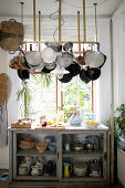 Hanging pot rack above glass-fronted cabinet