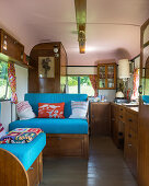 Wooden furnishings and blue upholstery in old caravan