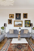 Bilderwand überm grauen Sofa im klassischen Wohnzimmer