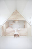 Child climbing into modern cubby bed surrounded by storage in attic bedroom