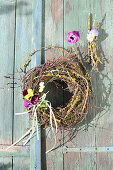 Wreath of moss and twigs with posies of violas hung on door