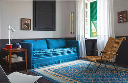 Blaues Sofa, Beistelltisch und indisches Sessel auf blau gemustertem Teppich