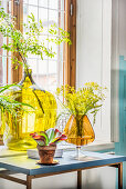 Demijohn and large amber glass used as vases in front of window