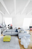Pale grey corner sofa in open-plan interior with exposed, white ceiling beams