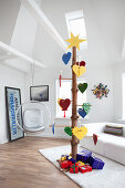Alternative Christmas tree made from tree trunk decorated with multicoloured love-hearts