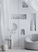 Sessel vor Wand mit Regalnischen im Wohnzimmer in Weiß