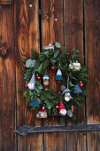 Christmas wreath decorated with knitted fir trees, gnomes and houses