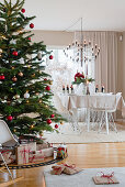 Gifts under Christmas tree in beige dining room