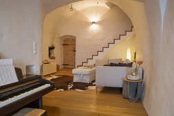 Piano in rustic living room with vaulted ceiling and staircase
