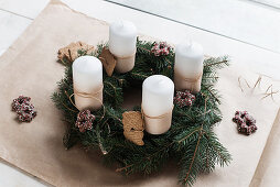 Handmade Advent wreath with fir branches, biscuits and white candles