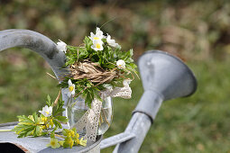 A small bouquet of wood anemones and primrose flowers with a grass cuff and lace ribbon, 
