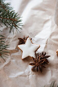 Cinnamon star biscuits, star anise and fir branches on brown paper