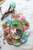 Golden tin lid surrounded by frame made from paper fans