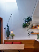 Dining table, bench and houseplants below light shaft