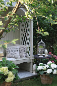 Arbour bench hidden in garden with hydrangeas planted in baskets