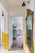 Antique gilt-framed mirror in hallway with yellow painted dado