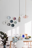 Plates decorating walls above set table in dining room
