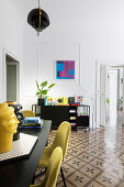 Yellow chairs around dining table in living room with tiled floor