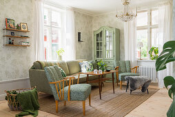 Green upholstered furniture, dresser and patterned wallpaper in living room